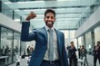 © CYBERUSS - Confident Indian Businessman Showing a Fighting Pose, Handsome Manager Gestures Raising Fists in Modern Office, Male Entrepreneur Celebrating Success.