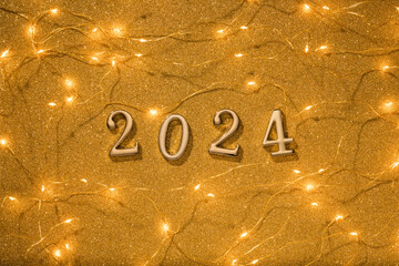 Poster - Golden numbers 2024 with Christmas lights on gold glitter texture background. 2024 new year coming