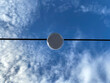 Lighting lamp hanging on electric cable on blue sky background. 