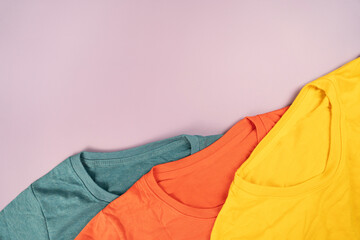 Wall Mural - close up of rolled colorful t shirt clothes on pink table background, travel and lifestyle concept