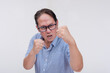 A middle aged asian man threatens to hit someone with his fist if they come closer. A hotheaded dad putting his guard stance up. Isolated on a white backdrop.