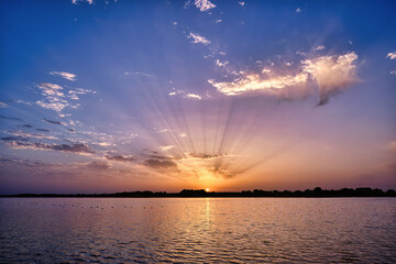 colorido, nuboso y espectacular amanecer en un lago rodeado de centenares de aves.