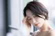 アジア系（日本人）女性のビューティーイメージ　アンニュイな表情で俯いて考える物思いにふける憂鬱や頭痛のイメージのクローズアップ