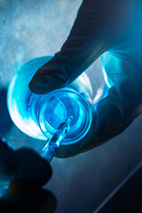 Wall Mural - blue science experiment bottle,bottle of water in the hand of a scientist by dropping liquid into a 