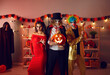Portrait of three people dressed up as spooky creepy evil characters with scary makeup on faces. Group of adult male and female friends standing together in decorated room at Halloween costume party