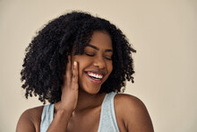 Happy Young Adult African American Woman Beauty Female Model, Pretty 20s Black Lady With Curly Hair Beautiful Face Advertising Skin Care Products Isolated At Beige Background. Aesthetic Authentic Shot