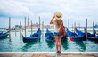 Rear view of woman standing on embarkment in Venice, Traditional gondola on grand canal, Italy- travel,tour tourism,vacation in Europe