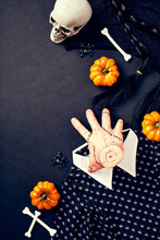 Halloween Party Elements. Flat Lay Served Hand, Pumpkins, Bones, Spiders, Wednesday Dress And Wig Hair On Dark Background.
