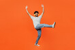 © ViDi Studio - Full body young smiling happy Indian man he wears t-shirt casual clothes listen to music in headphones raise up hands dance isolated on orange red color background studio portrait. Lifestyle concept.