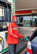 african american man attendant in red uniform and a smiley face at the gas pump, filling a small car