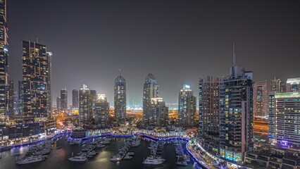 Poster - Panorama showing Dubai marina tallest skyscrapers and yachts in harbor aerial night.