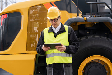Aufkleber - Worker in a helmet with a digital tablet on the background of construction machine