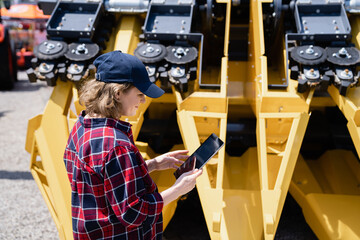 Fototapete - Woman farmer with digital tablet on a background of harvester. Smart farming concept