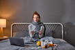 © alfa27 - young red-haired sick girl holding smart phone sneezing, bless you. closeup portrait, laptop , pills, medicine antiviral antibiotics antipyretic painkillers are on bed