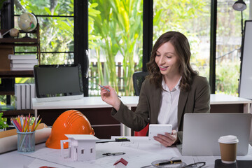 Wall Mural - An architect woman or engineer woman working on blueprint with model house in office, architectural concept.