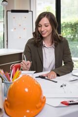 Wall Mural - An architect woman or engineer woman working on blueprint with model house in office, architectural concept.