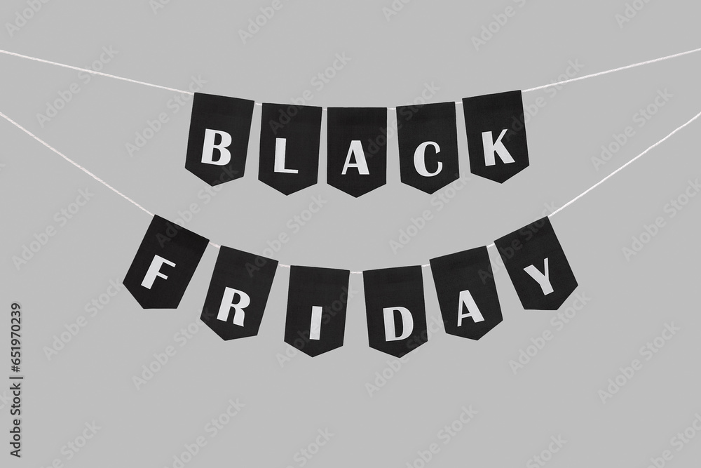 Flags with text BLACK FRIDAY hanging on rope against grey background