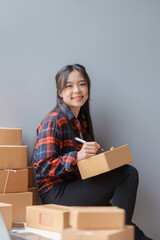 Wall Mural - E-commerce Entrepreneurship. Asian Female Online Seller Packing Orders for Internet Sales. Efficient Online Sales. Asian Female owner Packaging Products for Delivery.