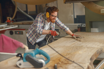 Woodworker is cleaning saw from sawdust working in carpentry workshop. High quality photo