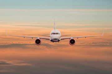 Wall Mural - Passengers commercial airplane flying above clouds in sunset light, straight view. Concept of fast travel, holidays and business.