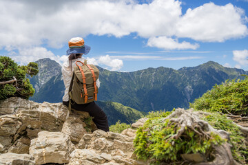 Poster - Young hiker backpacker female sitting on the cliff