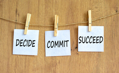 Wall Mural - Decide commit succeed symbol. Concept word Decide Commit Succeed on beautiful white paper on wooden clothespin. Beautiful wooden background. Business decide commit succeed concept. Copy space
