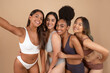 © Prostock-studio - Four smiling beautiful diverse women in underwear talking selfie, smiling at camera, isolated on beige studio background