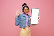Beautiful Asian teen woman holding smartphone mockup of blank screen and shows ok sign on pink background.