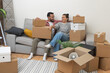 © olga_demina - Home Sweet Home: A happy young married couple relaxes on the sofa, surrounded by numerous cardboard boxes, exhausted yet overjoyed after successfully moving to their new apartment