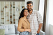 © Home-stock - Portrait of young romantic indian couple embracing and smiling, posing in living room interior, enjoying time together, free space