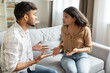 © Home-stock - Angry indian couple having quarrel experiencing crisis in relationship, sitting on sofa and having conflict at home. Marital problems, divorce concept