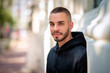 © sepy - A portrait of a stylish young man standing in a city street and smiling