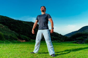 Canvas Print - Handsome young man standing and breathing in mountain valley at twilight