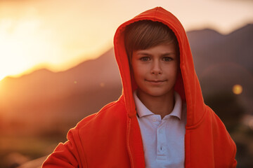 Wall Mural - Portrait of handsome boy in orange hooded sweatshirt at sunset light