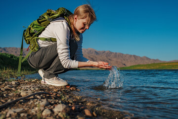 Wall Mural - Young woman tourist with splash of clean water in mountain river