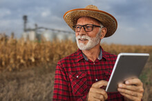 Farmer With Tablet In Front Of Grain Silos