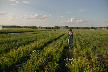 Female agronomist with clipboard standing field during harvesting. Agricultural occupation concept