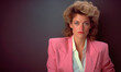 Iconic 1980s Style: Woman Portrait with Shoulder Pads and Voluminous Hair. Gray Background