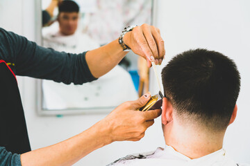 Barber gives hair to male customer with clippers and comb in barber shop