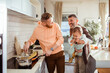 © Marko Geber - Gay male couple and their adopted son preparing lunch together at home