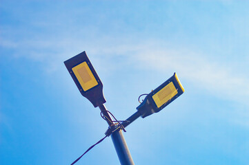 two street lamps on a pole against a blue sky background