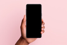 Hand holding smartphone with a black blank screen isolated on a pink background