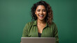© Noman Shaikh - Young happy Latin woman winner holding a laptop isolated on a green background. Excited euphoric female model using computer winning online celebrating new great job offer with yes gesture concept.