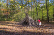 © Cavan - Young boy using sticks to build shelter in woods.