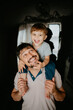 © Westend61 - Smiling father carrying son at home