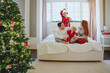© Westend61 - Family spending leisure time on bed near Christmas tree at home