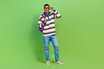 Poster - Full body photo of young man smile touch eyeglasses posing model wear rucksack back to cambridge college isolated on green color background