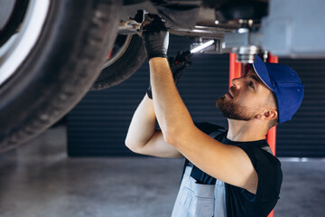 Wall Mural - Auto mechanic lifting car and doing check up on car service