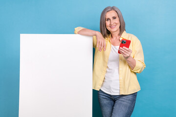 Sticker - Portrait of pretty aged lady hold smart phone demonstrate empty space ad poster isolated on blue color background