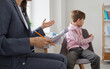 © Studio Romantic - Child at psychologist's office. Kid refuses to talk, turns away and avoids eye contact. Resentful boy with communication and behaviour problems sitting on chair during therapy session with specialist